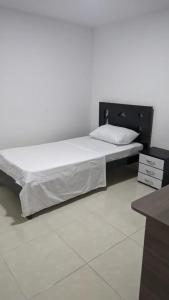 una camera con un grande letto con testiera nera di Acogedor apartamento La Nubia a Manizales