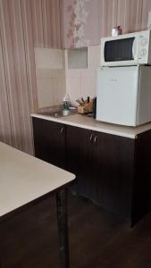 een keuken met een magnetron en een koelkast bij Готель Деметра in Charkov