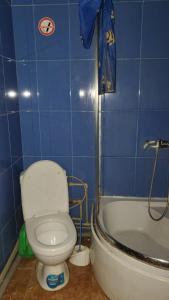 een blauwe betegelde badkamer met een toilet en een bad bij Готель Деметра in Charkov