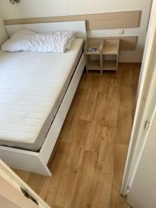 een kleine slaapkamer met een bed en een houten vloer bij Luxueuze stacaravan 4pers met terras en tuintje Bredene (2010) in Bredene
