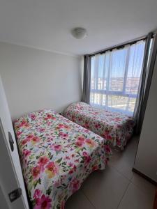 1 dormitorio con 2 camas y ventana en Departamento junto a la playa "Marina Horizonte", en Coquimbo