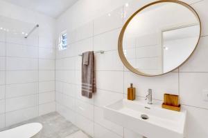 a white bathroom with a sink and a mirror at Villa Kiwi 3 min to the Beach with Private Magnesium Pool in Belnem