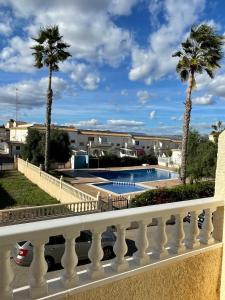 un balcón con palmeras y una piscina en Villa Dulce, en Gran Alacant