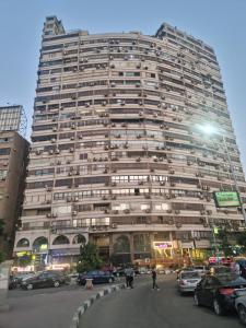 Jasmine Nile Sky Hotel في القاهرة: مبنى كبير به سيارات تقف في موقف للسيارات