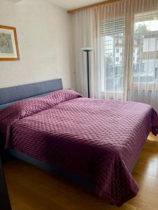 a purple bed in a bedroom with a window at Crans center and close to the ski lifts in Crans-Montana