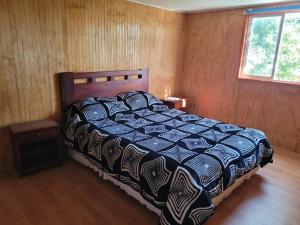 a bedroom with a bed with a blue and white comforter at Casa acogedora in Valdivia