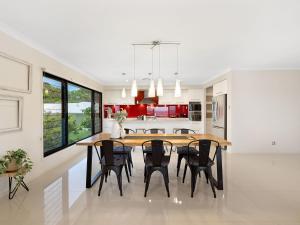 comedor y cocina con mesa de madera y sillas en Koala Vista with Panoramic Views & Pool, en Pottsville