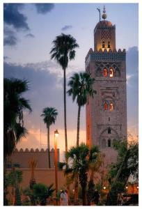 una torre dell'orologio con palme di fronte a un edificio di Dúplex Goytisolo a Marrakech