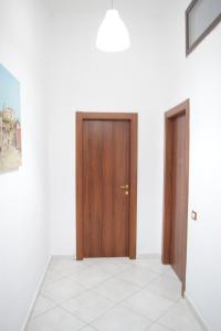 pasillo con puerta de madera y paredes blancas en B&B Il Sole, en Torre Annunziata