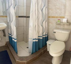 a bathroom with a toilet and a shower curtain at Hostal Casa Latina in Manta