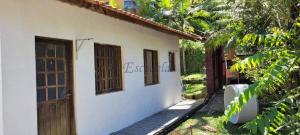 a white house with wooden doors and a yard at Cantinho da Eli - Pousada com Piscina in Mairiporã
