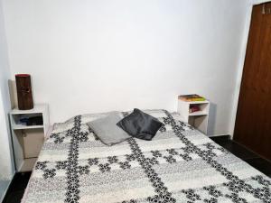 a bedroom with a bed with a black and white quilt at Cantinho da Eli - Pousada com Piscina in Mairiporã