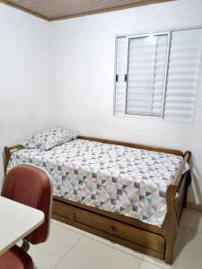 a small bed in a room with a window at Cantinho da Eli - Pousada com Piscina in Mairiporã