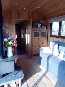 Sala de estar de una cabaña de madera con sofá en River Meadow Retreat en Uffculme