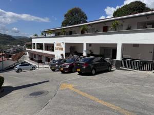 un estacionamiento con autos estacionados frente a un edificio en Hotel Santorini en San Gil