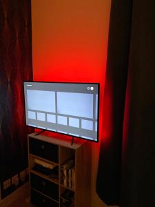 a flat screen tv sitting on a stand with a red light at Appartement Moderne, proche Porte de Versailles et Gare de Clamart in Malakoff