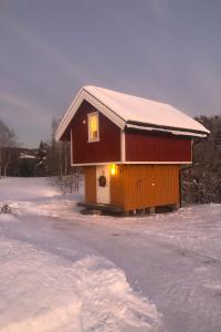 una pequeña casa con nieve en la nieve en Unik overnatting i Stabbur/Minihus, en Lunde