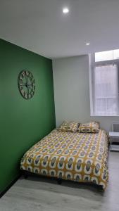 sypialnia z łóżkiem i zegarem na ścianie w obiekcie Studio Hibiscus tout confort, rénové w mieście Saint-Quentin
