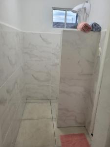 uma casa de banho com um chuveiro e azulejos de mármore branco em Suíte 2 com sala em Lages