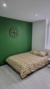 sypialnia z łóżkiem i zegarem na zielonej ścianie w obiekcie Studio Hibiscus tout confort, rénové w mieście Saint-Quentin