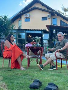 Ein Mann und eine Frau, die auf Stühlen im Gras sitzen in der Unterkunft Pousada Vilagio Chapada in Chapada dos Guimarães