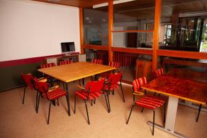 Jaala Hotel في كووفولا: غرفة طعام مع كراسي حمراء وطاولة خشبية