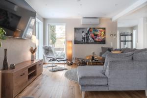 sala de estar con sofá gris y silla en Guestly Homes - 4BR Cozy Corporate Villa, en Piteå