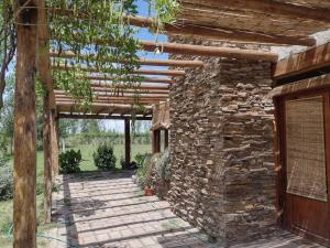 a stone building with a wooden pergola at Posada Los Nogales in Junín