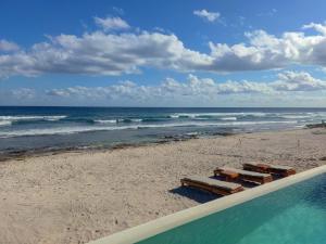 a beach with a swimming pool next to the ocean at Luxury Romantic Getaway - 1 Bedroom - Steps from the Beach - Bahia Tankah Tulum in Tulum