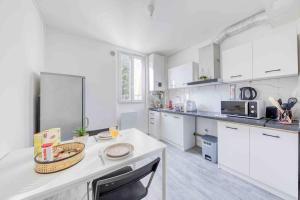 une cuisine avec des placards blancs et un comptoir blanc dans l'établissement Appartement Cosy I Proche de la Porte de Versailles Paris, à Malakoff