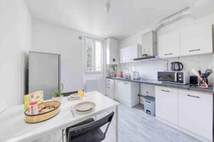 Una cocina con gabinetes blancos y una encimera blanca. en Appartement Cosy I Proche de la Porte de Versailles Paris, en Malakoff