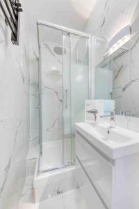 Un baño blanco con ducha y lavabo. en Appartement Cosy I Proche de la Porte de Versailles Paris, en Malakoff 16 fotos más
