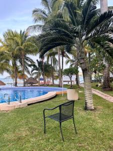 a black bench sitting in the grass next to a pool at Front beach private room with shared bathroom in Cancún
