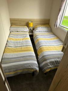 two beds in a small room with a window at Primrose valley - Primrose Field 46 holiday home in Filey