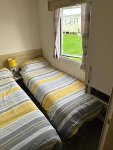 Primrose valley - Primrose Field 46 holiday home في Filey: سريرين يجلسون في غرفة مع نافذة