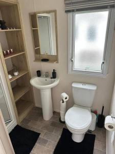 uma casa de banho com um WC branco e um lavatório. em Primrose valley - Primrose Field 46 holiday home em Filey