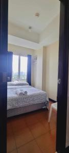 a bedroom with a large bed with a window at San Lorenzo place condo in Manila