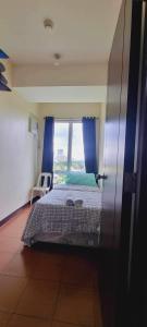 a bedroom with a bed with blue curtains and a window at San Lorenzo place condo in Manila