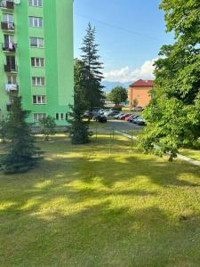 ein grünes Gebäude mit Bäumen auf einem Grasfeld in der Unterkunft Apartmán v centre mesta in Liptovský Mikuláš