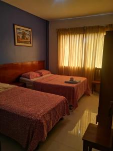 a hotel room with two beds and a window at Hostal Esplendor in Chiclayo
