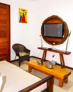 a living room with a tv and a table with a table at CASA SIMONI Trancoso in Trancoso