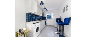 a kitchen with a washing machine and a blue chair at Comfortable and Stylish 1 BR flat - Sleeps 2 in London