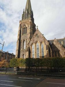 Una iglesia con una torre con un reloj. en Glasgow Center/West End Apartment, en Glasgow
