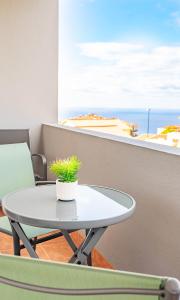 a table with a plant on a balcony with the beach at Serene Haven Retreat - Madeira Island in Caniço
