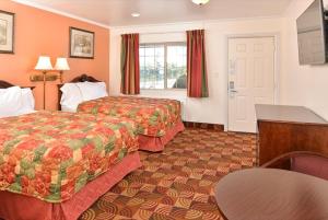 Cette chambre comprend 2 lits et une table. dans l'établissement Americas Best Value Inn & Suites Klamath Falls, à Klamath Falls