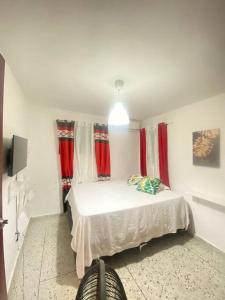 サンティアゴ・デ・ロス・カバリェロスにあるHermoso Apartamento centro ciudad, wifiのベッドルーム(赤いカーテン付きの白いベッド1台付)