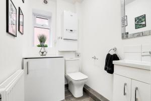 a white bathroom with a toilet and a sink at Modern contemporary with parking in Hough Green