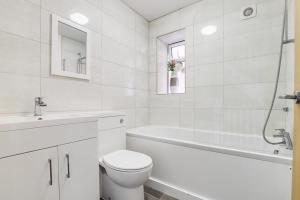 y baño blanco con aseo, bañera y lavamanos. en Modern contemporary with parking en Hough Green