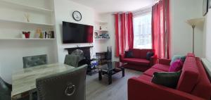 salon z 2 czerwonymi kanapami i telewizorem w obiekcie New Bubble Apartments w Londynie