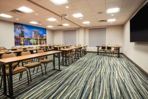 einen Konferenzraum mit Tischen und Stühlen und einem Flachbild-TV in der Unterkunft Wingate By Wyndham - Orlando International Airport in Orlando